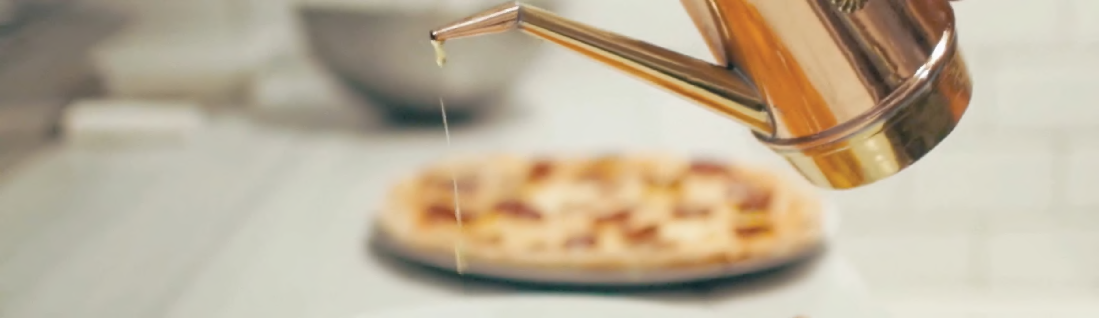 Pouring extra virgin olive oil on pizza